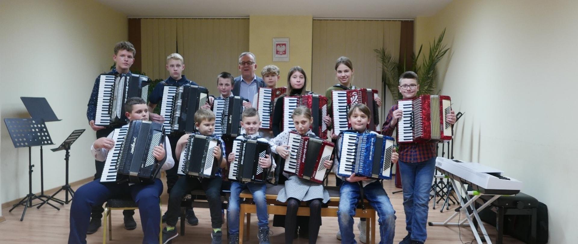 uczniowie klasy akordeonu ustawieni w dwóch rzędach trzymający akordeony