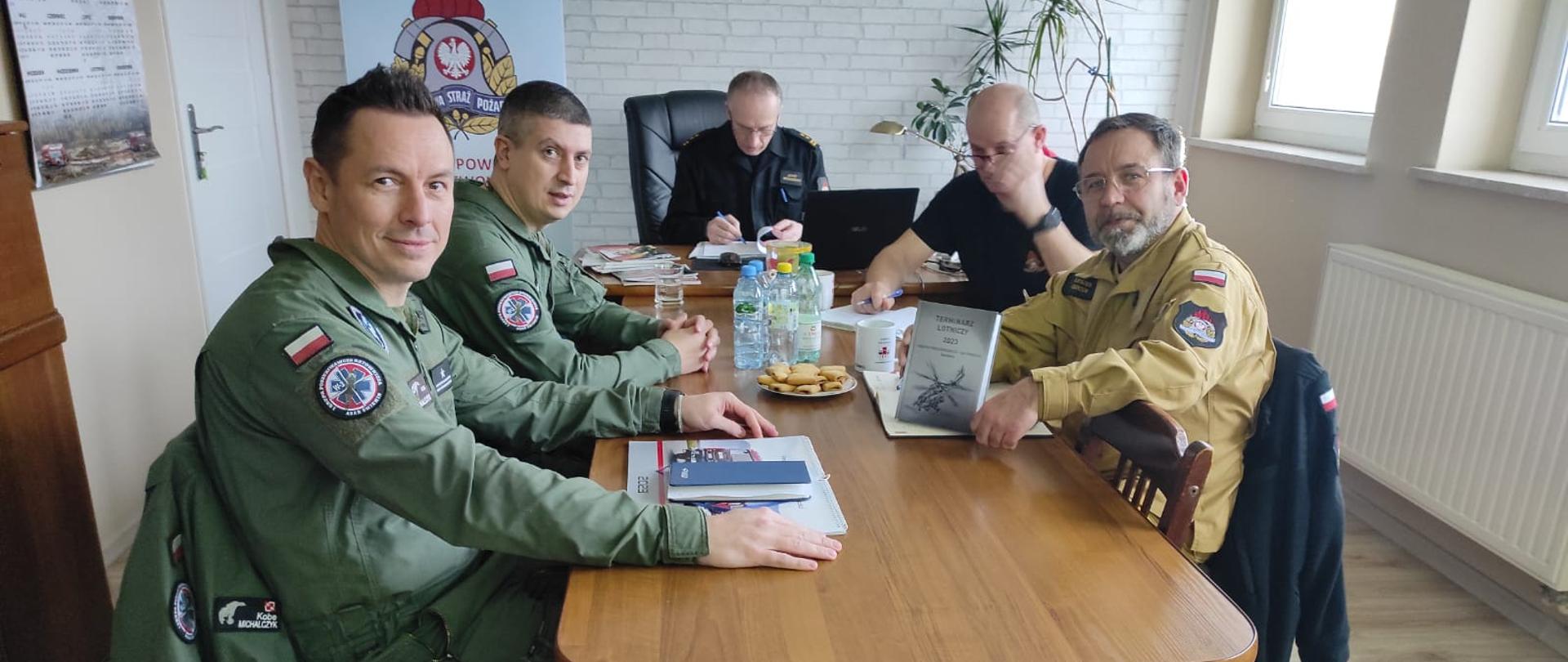 Zdjęcie przedstawia mężczyzn siedzących przy stole podczas omawiannia ćwiczeń.