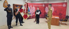 Zdjęcie przedstawia akt uroczystego ślubowania na sztandar nowoprzyjętego funkcjonariusza 
