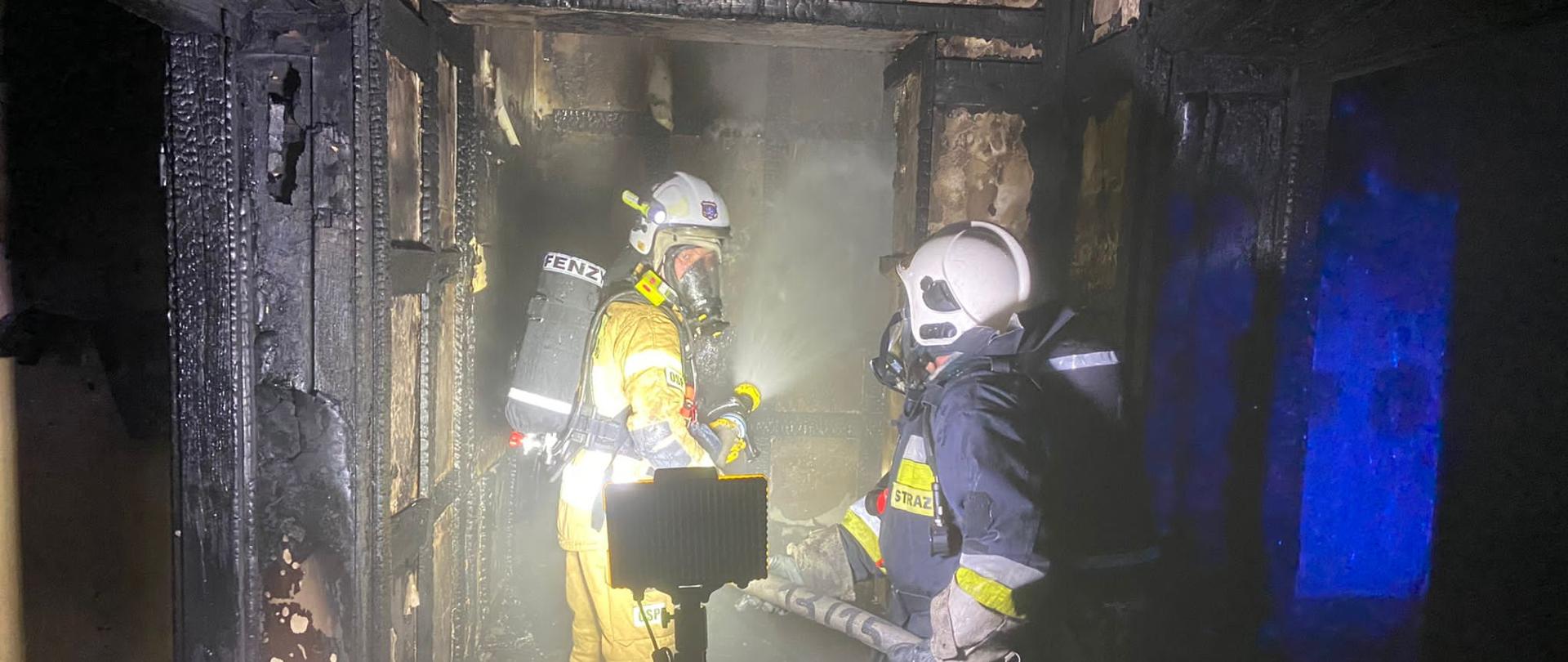 Na zdjęciu widać wnętrze spalonego budynku oraz strażaków pracujących wewnątrz 