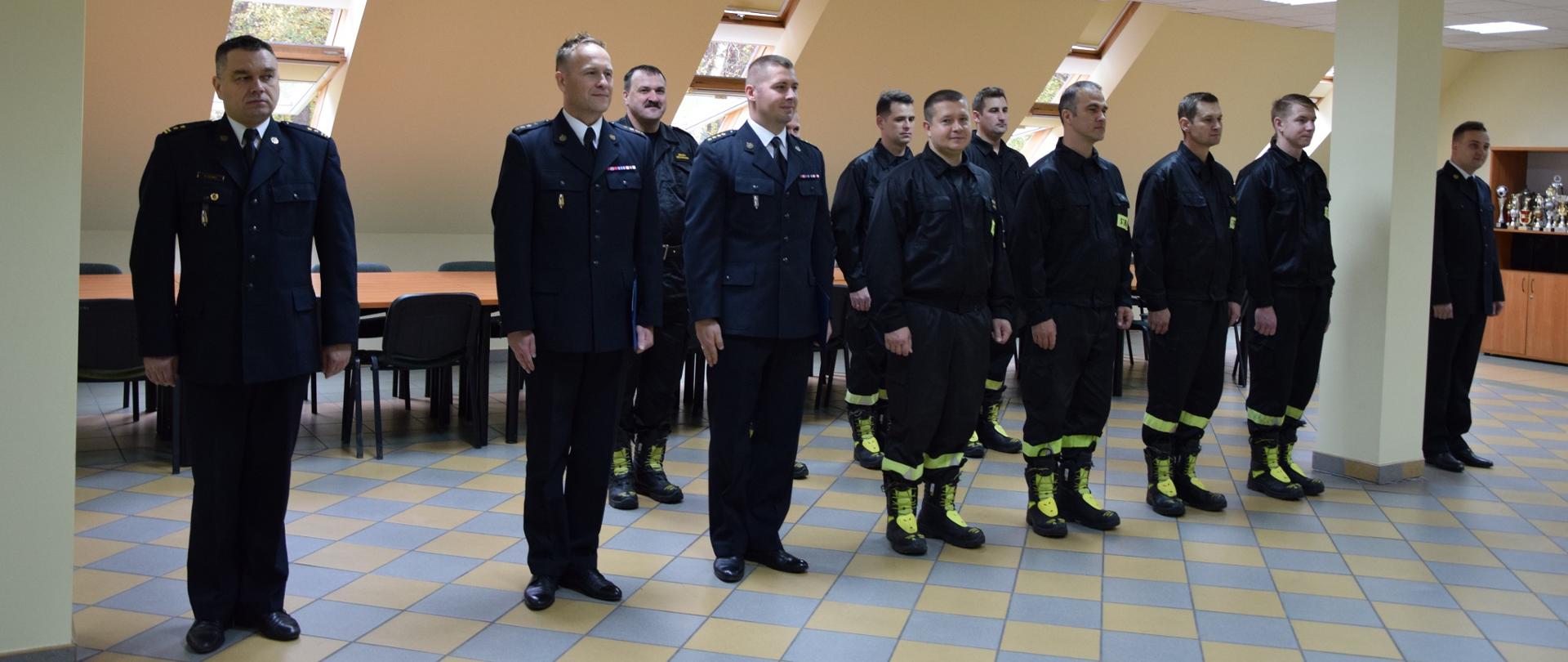 Na zdjęciu widać ustawionych w dwuszeregu strażakach w ubraniach galowych.