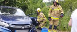 Uszkodzony samochód osobowy a obok strażacy