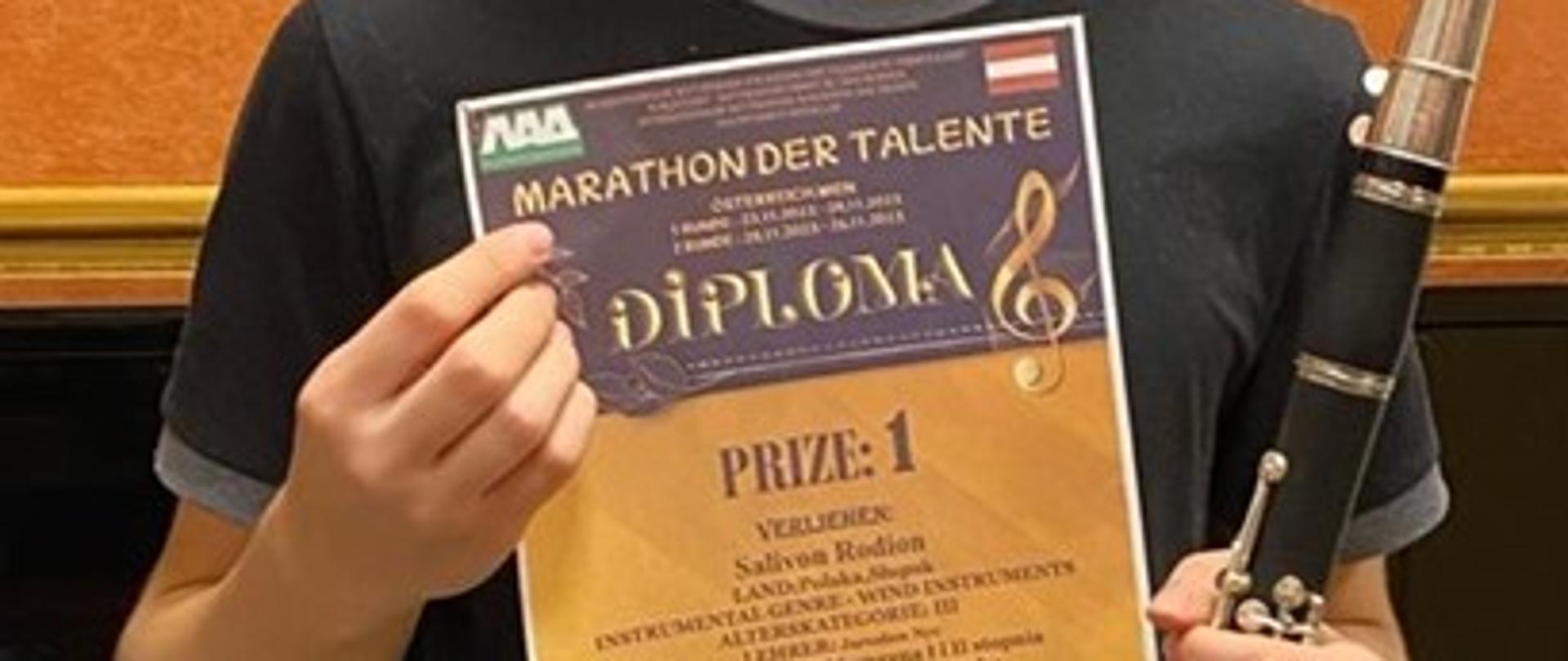 Uśmiechnięty chłopiec trzyma dyplom. 