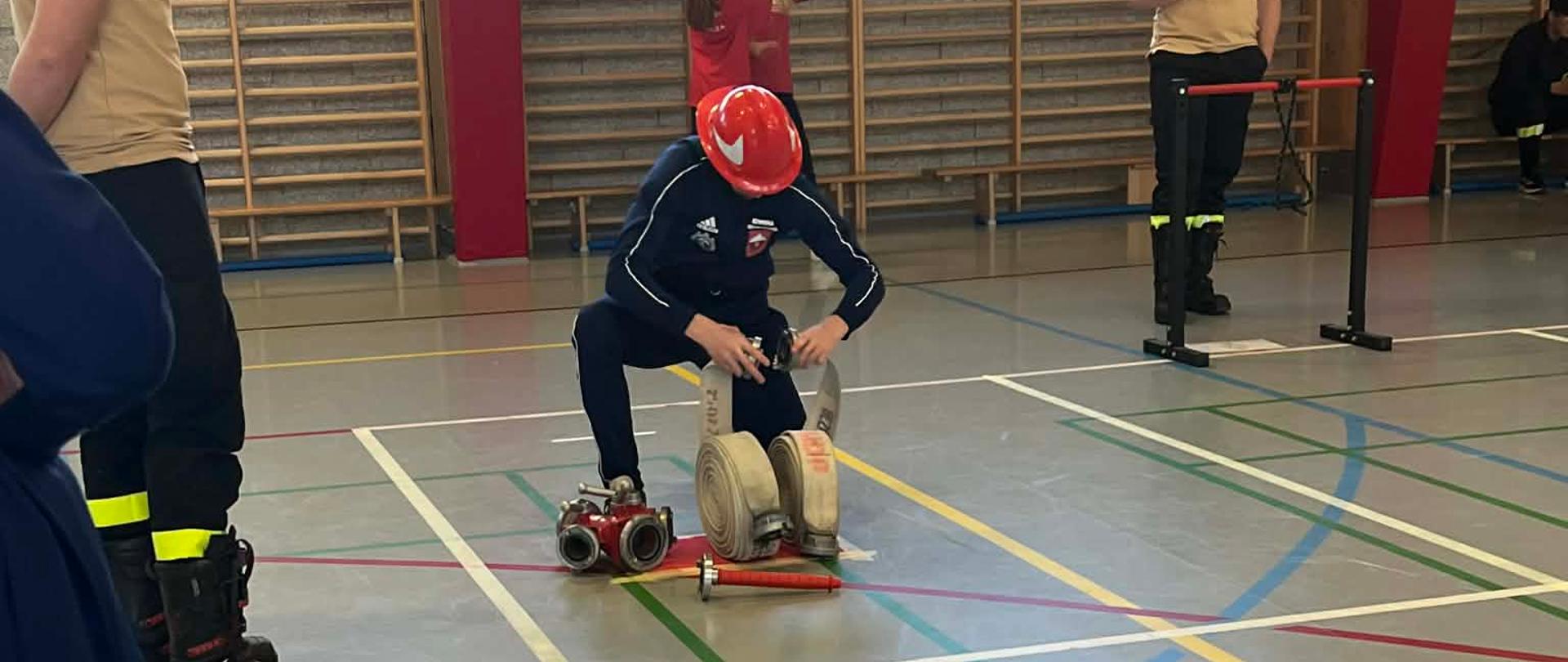 Zdjęcie przedstawia członków młodzieżowej drużyny pożarniczej podczas zawodów powiatowych