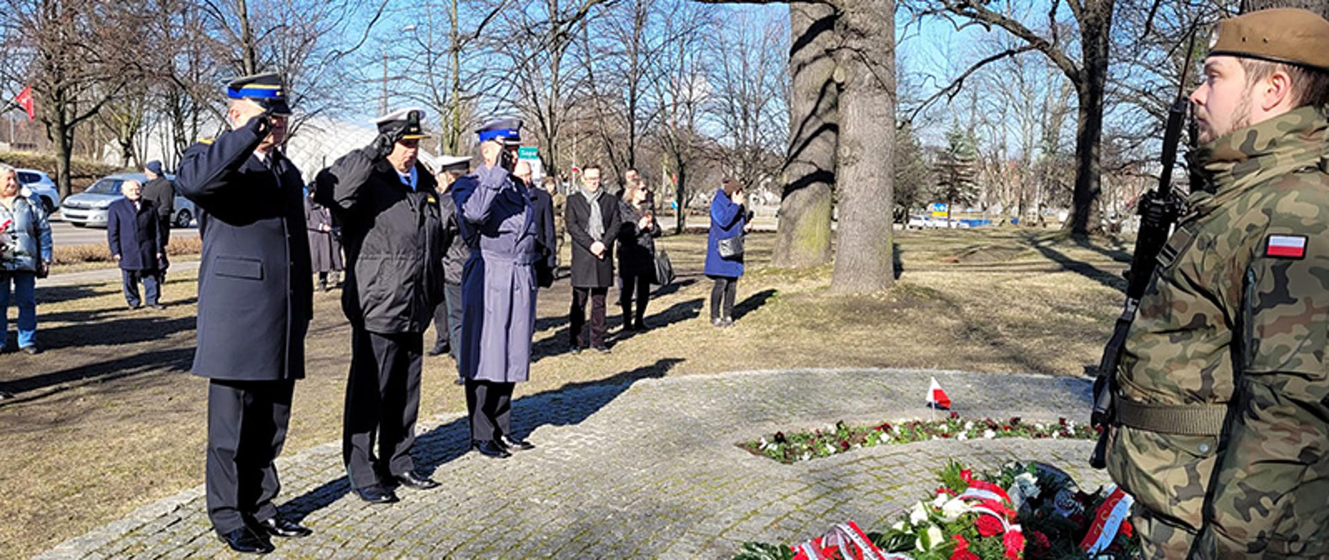 Przedstawiciele służb podległych Ministerstwu Spraw Wewnętrznych i Administracji oddają honory przed pomnikiem po złożeniu wieńca.