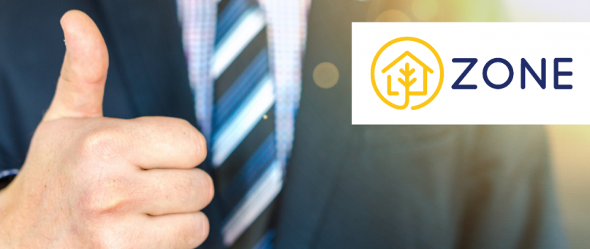 Mężczyzna w granatowym garniturze i niebieskim krawacie pokazujący kciuk w górę; obok logo „ZONE” z ikoną domu i drzewa w żółtym kole.