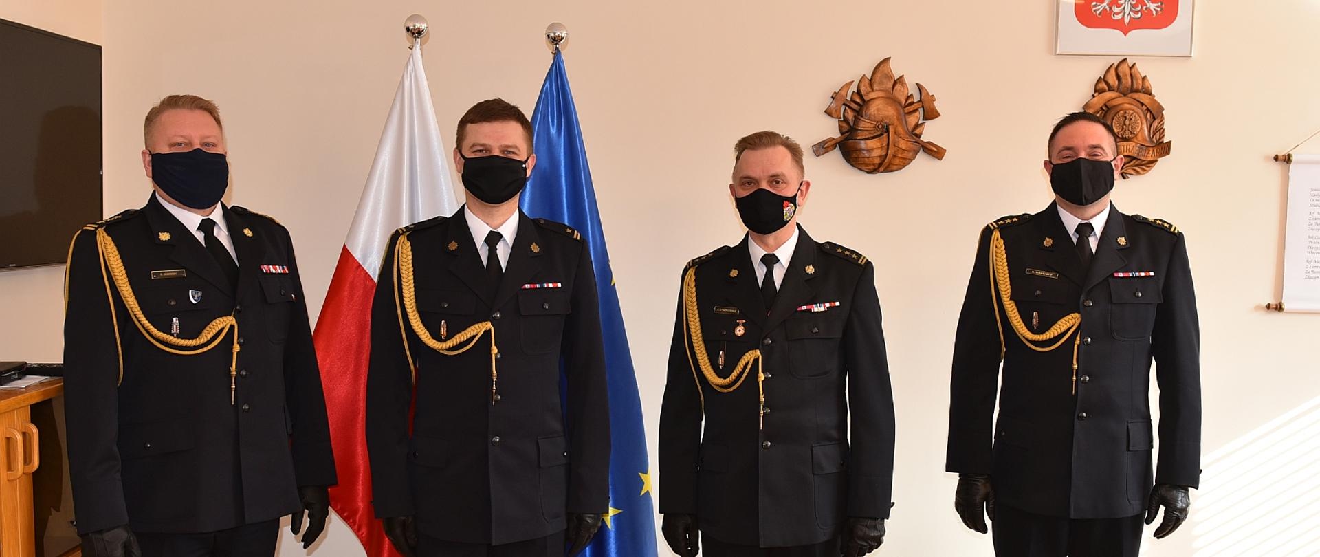 na zdjęciu znajduje się 5ciu strażaków w mundurach wyjściowych w tle flaga PL i UE.