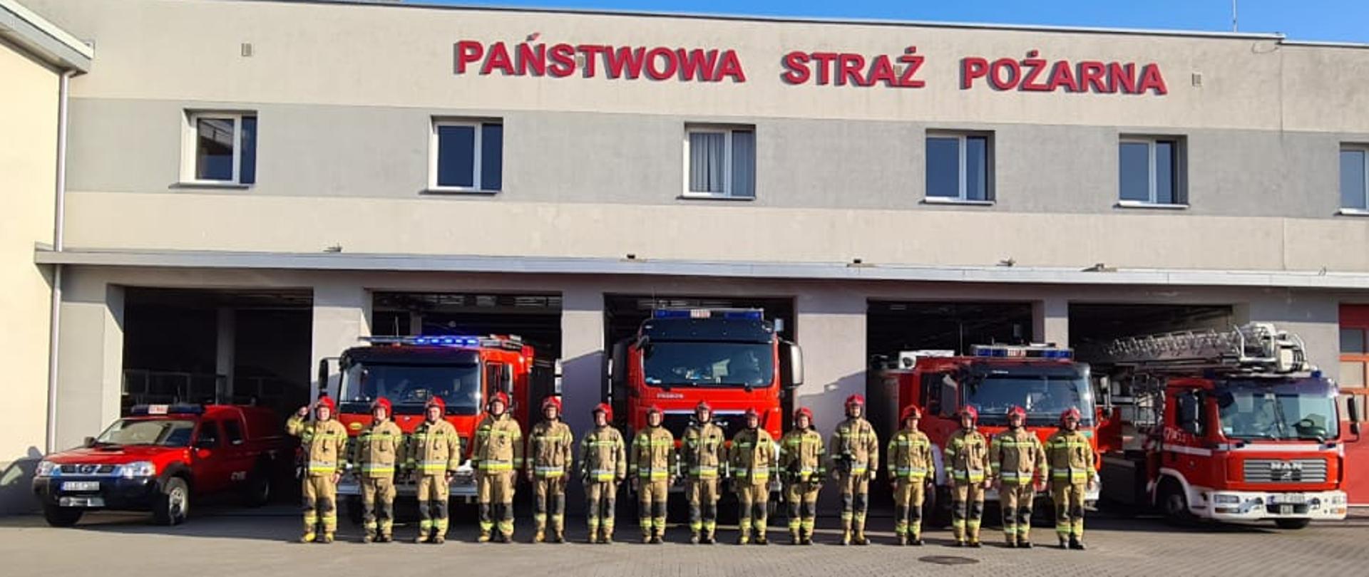 Na zdjęciu widoczni strażacy na tle budynku Komendy Powiatowej Państwowej Straży Pożarnej w Lęborku 