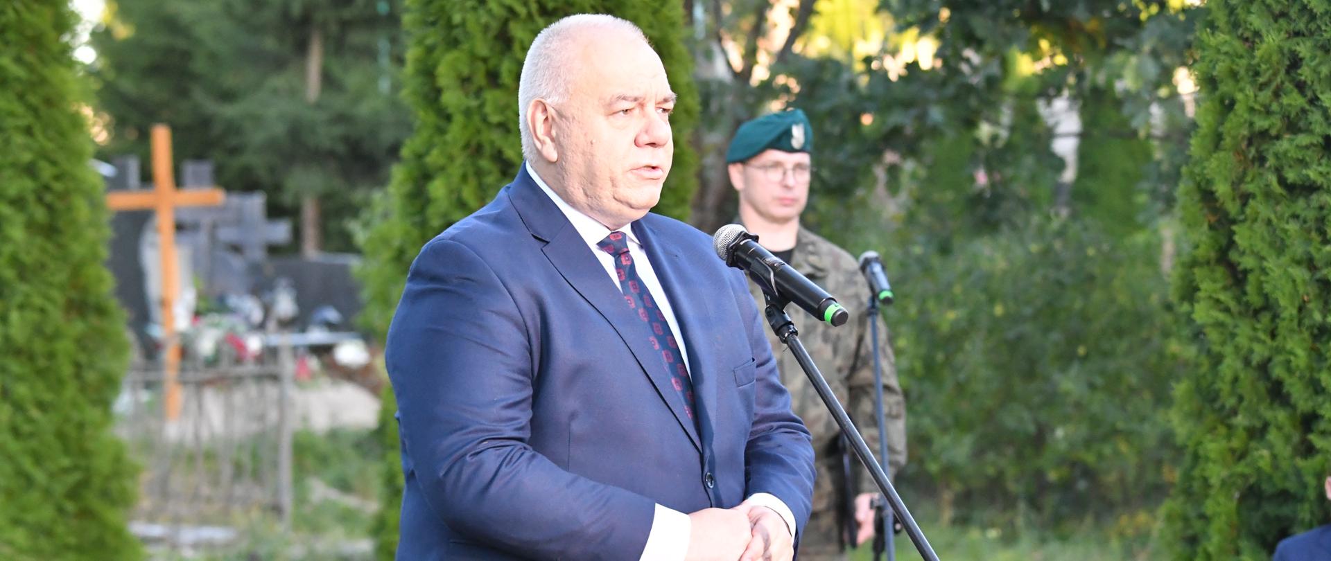 Minister Jacek Sasin stoi za mikrofonem. Z tyłu żołnierz.