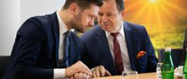 uczestnicy spotkania: wiceminister Kamil Bortniczuk i marszałek Władysław Ortyl siedzą przy stole i rozmawiają ze sobą