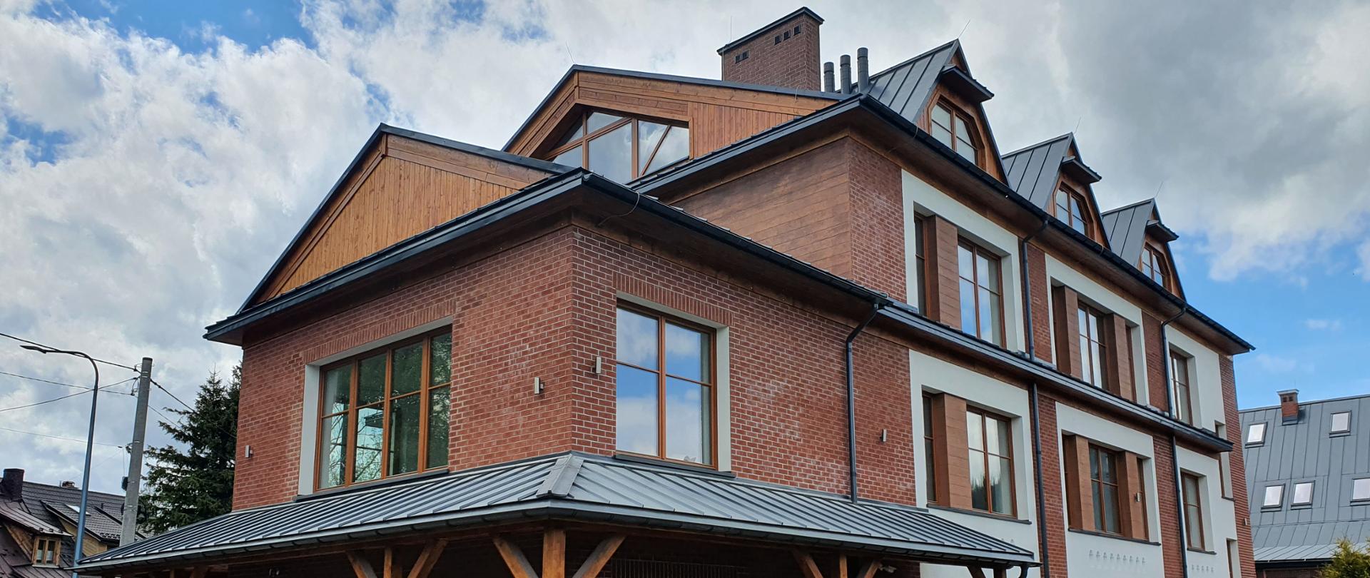 Na zdjęciu w części centralnej usytuowany jest budynek Państwowego Liceum Sztuk Plastycznych im. Antoniego Kenara w Zakopanem.
Elewacja budynku wykonana jest z czerwonej cegły, wykończenia wokół okien są białe. Dach spadzisty w kolorze szarym. Przed budynkiem znajduje się ogrodzenie również z cegły z wypełnieniami elementów z drewna. 