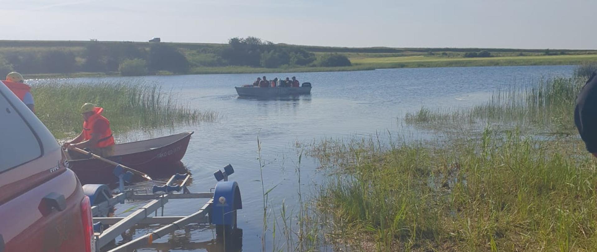 Fotografia przedstawia działania poszukiwawcze na jeziorze w celu odnalezienia zwłok topielca.
