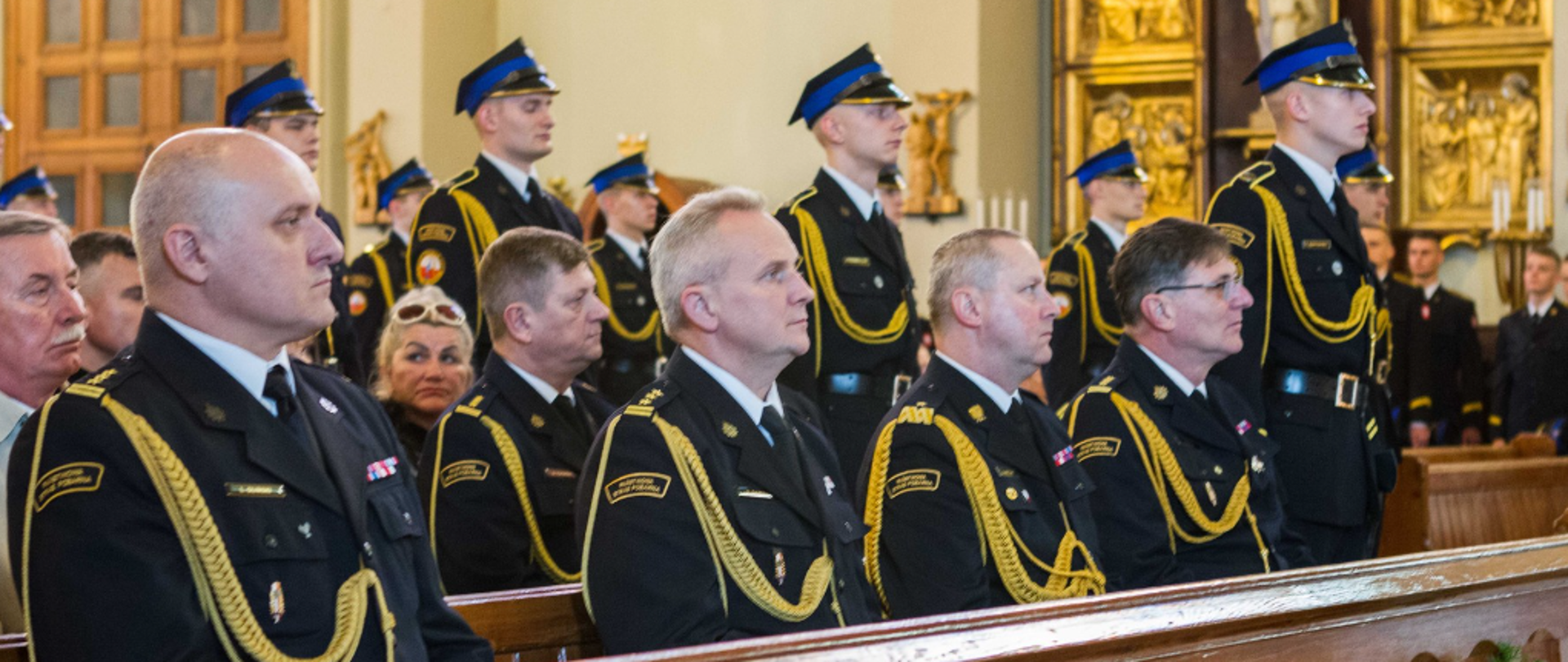 strazacy w mundurach ze sznurem siedzą w kościele