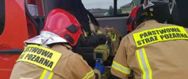 Zdjęcie zrobione w dzień. Na zdjęciu widać samochód pożarniczy oraz dwóch strażaków i przyrządy pomiarowe. 