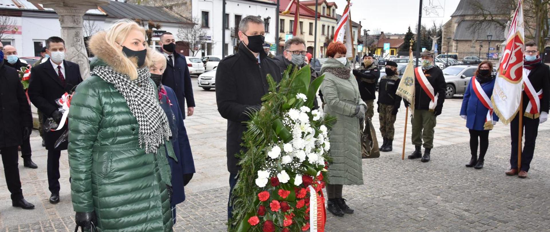 Grupa ludzi podczas złożenia wieńców w miejscu upamiętnienia Powstania Styczniowego. W centralnym punkcie zdjęcia Wicewojewoda Mazowiecki Artur Standowicz. 