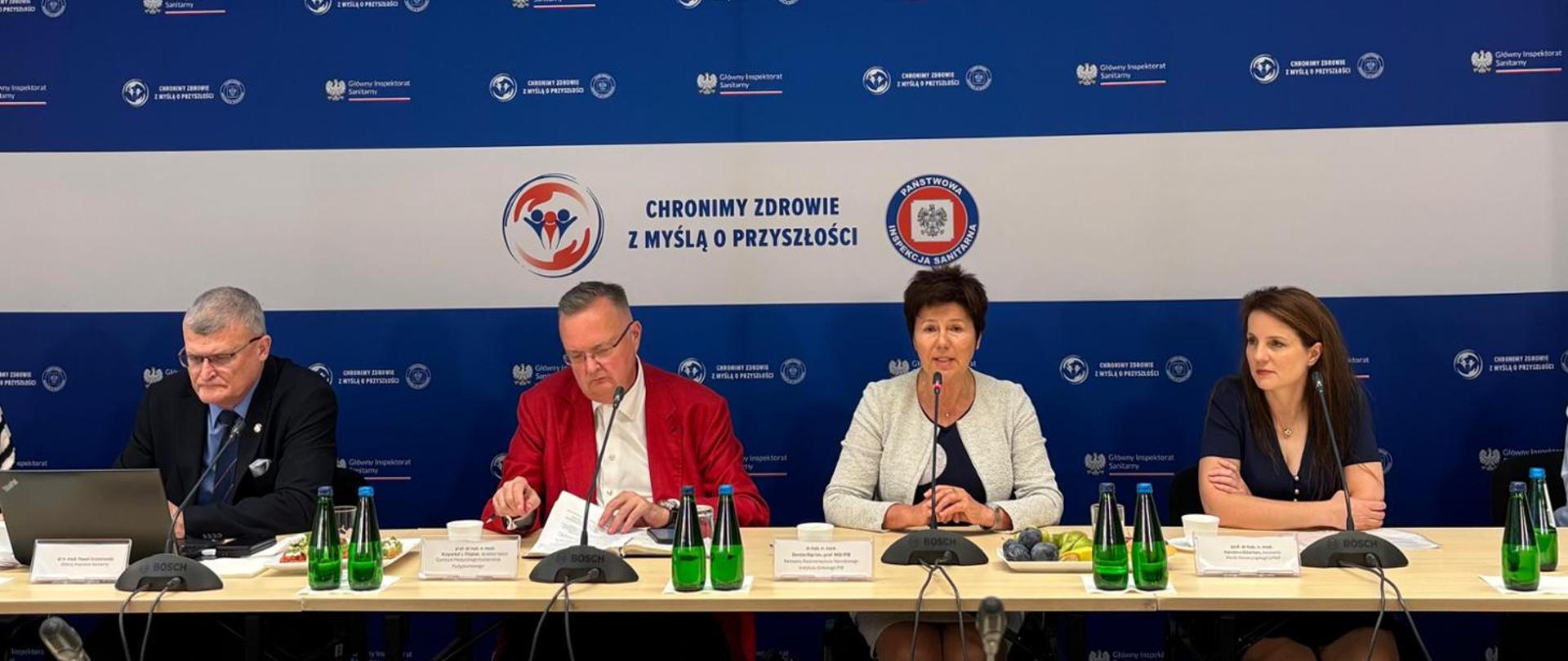 zdjęcie przedstawia 4 dorosłe osoby siedzące przy stole podczas konferencji