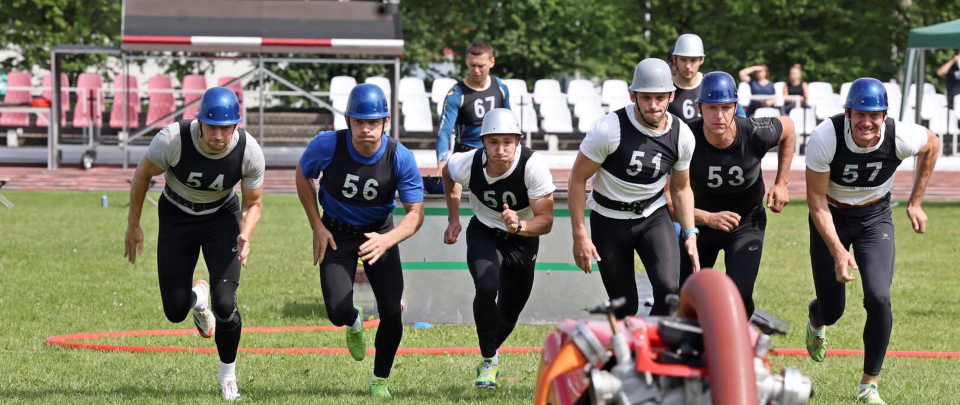 42. Mistrzostwa Polski w Sporcie Pożarniczym zakończone - reprezentacja woj. podlaskiego - zdjęcie grupowe, w tle trybuny, strażacy biegną do zbiornika brezentowego z wodą
