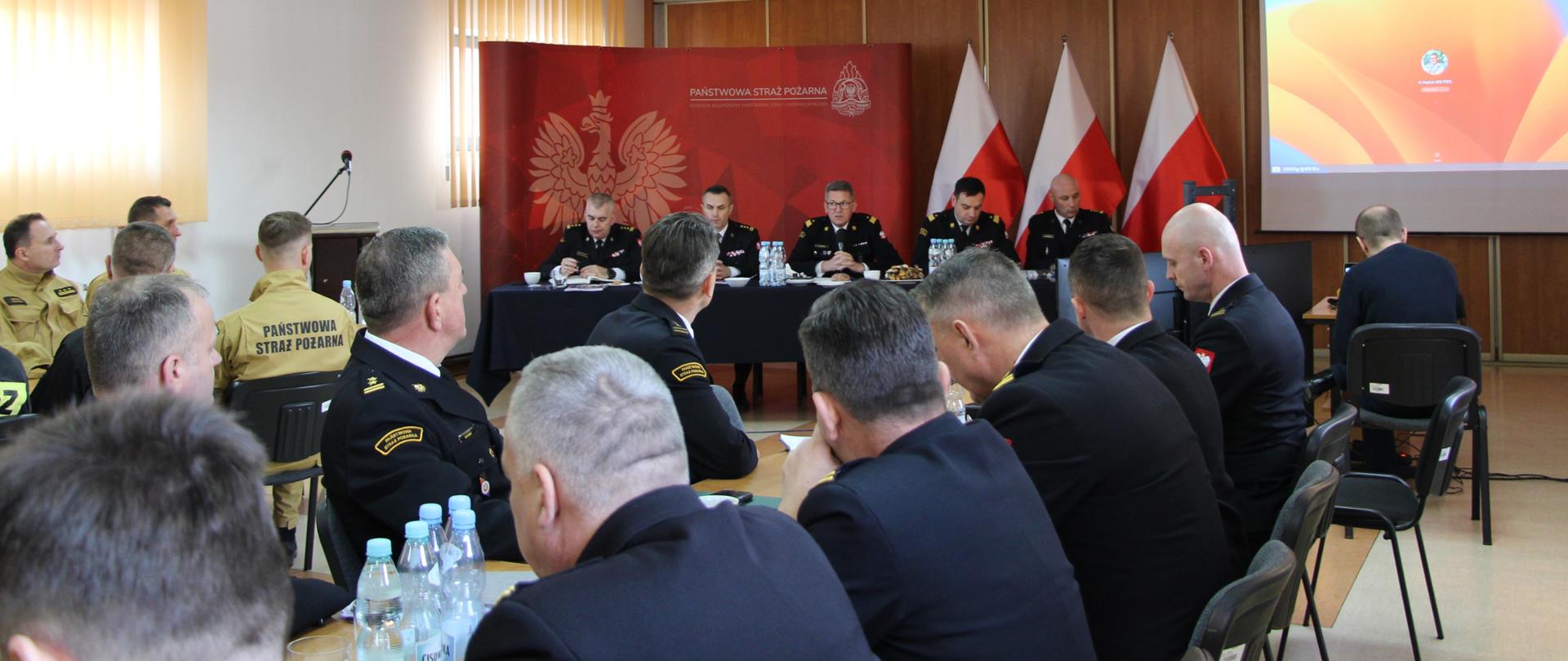Zdjęcie przedstawia funkcjonariuszy podczas spotkania z nadbryg. Krzysztofem Hejdukiem zastępcą komendanta głównego Państwowej Straży Pożarnej. 