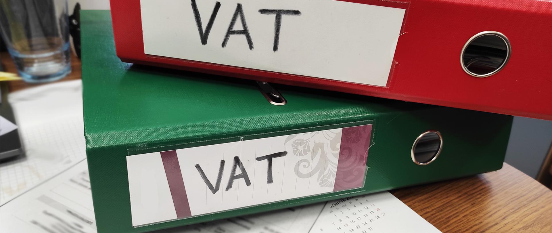 Dwa segregatory na biurku, na etykietach napisane VAT
