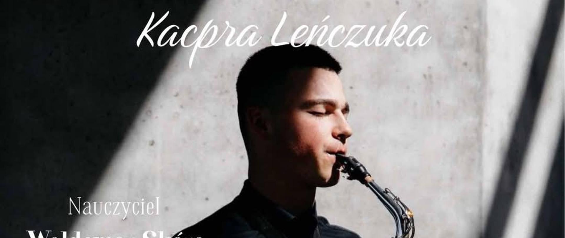 Na plakacie widnieje młody mężczyzna grający na saksofonie, ubrany na czarno, stojący w silnym świetle rzucającym wyraźny cień na ścianę za nim. Na górze znajduje się duży napis: „Recital Dyplomowy Kacpra Leńczuka”. Poniżej, po lewej stronie widnieje informacja: „Nauczyciel Waldemar Skóra, przy fortepianie Piotr Stopa”. W prawym dolnym rogu znajduje się informacja o terminie wydarzenia: „14 maja, godz. 18:00, Aula PSM w Zamościu”. Tekst na plakacie ma różne wielkości i kolory – głównie biały – co nadaje mu elegancki i profesjonalny charakter.