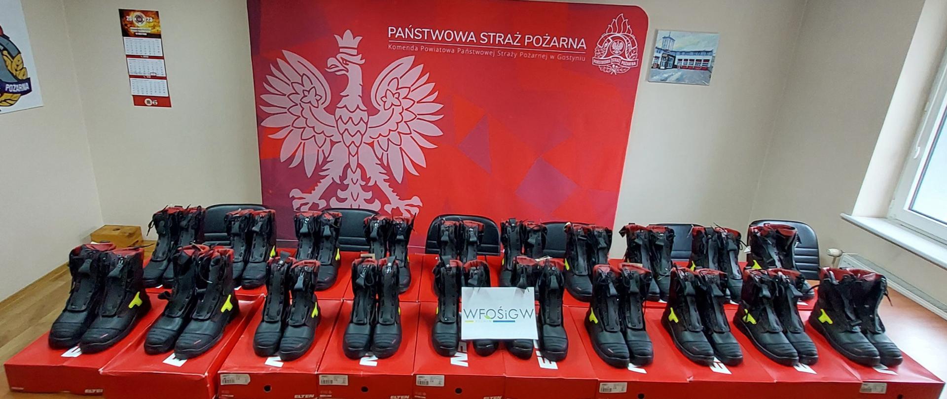 20 par skórzanego obuwia strażackiego. Buty wyciągnięte są z kartonów i stoją na nich na stole.