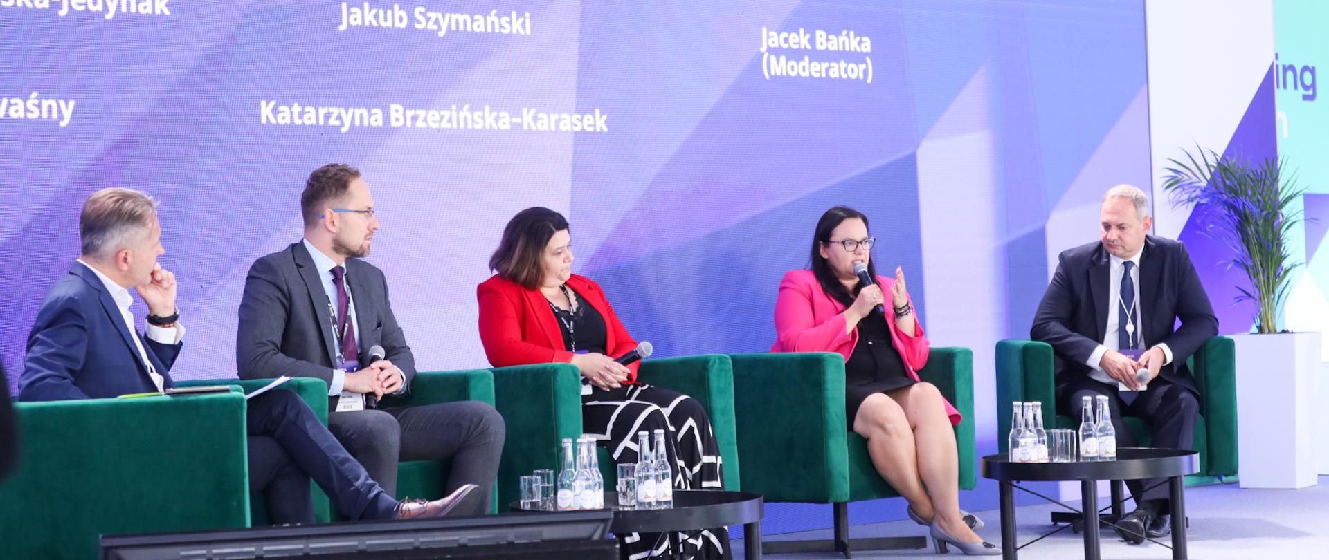 Pięć osób podczas debaty siedzi w fotelach na scenie. Druga od prawej wiceminister Małgorzata Jarosińska-Jedynak mówi do mikrofonu.