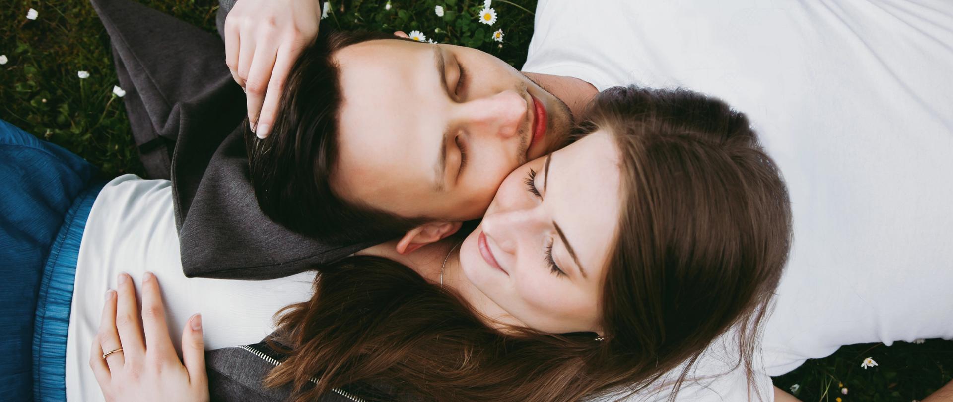 Para leżąca na trawie wśród stokrotek