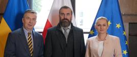 Minister Wieczorek, mężczyzna z brodą i minister Nowacka stoją w rzędzie, za nimi flagi Polski, Ukrainy i UE, dalej okno.