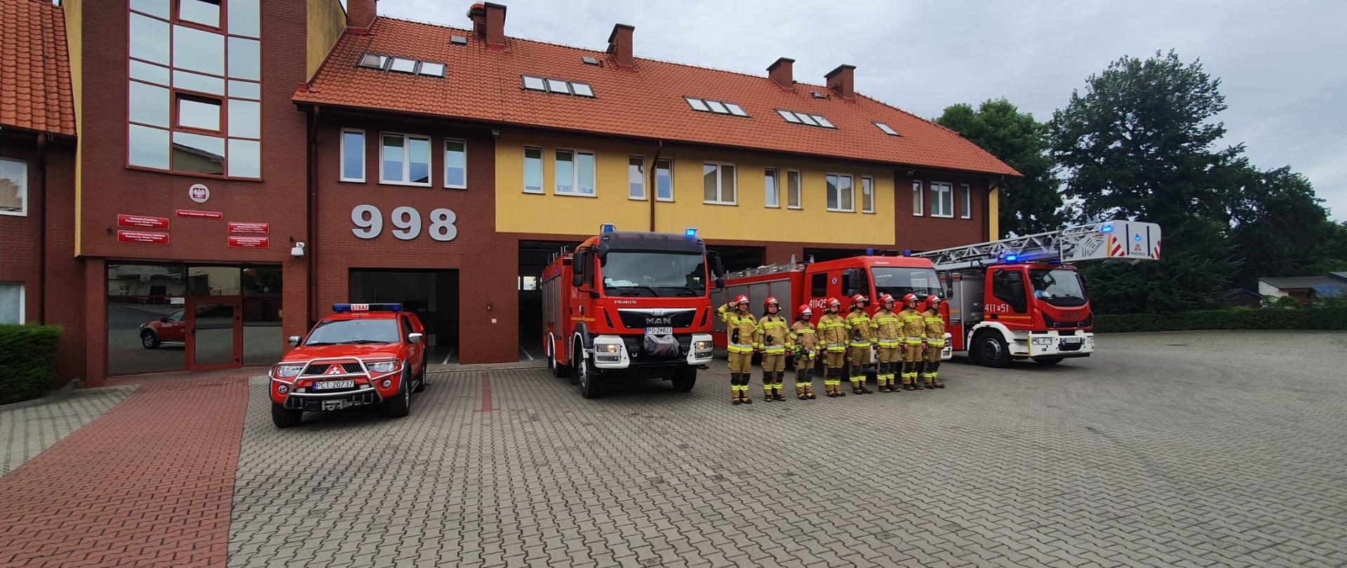 Strażacy w oddają honor przed strażnicą 
