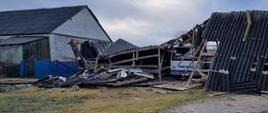 zniszczona stodoła w Bojarach, gmina Kosów Lacki, gdzie całkowitemu zawaleniu. Widać połamane arkusze eternitu i uszkodzone drewniane elementy stodoły, w środku samochód ciężarowy