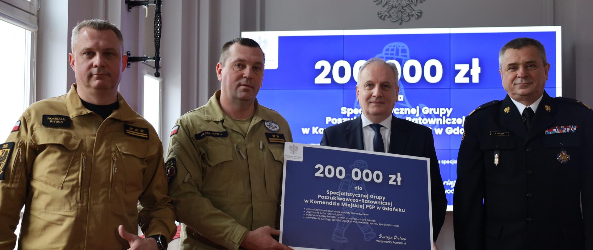 Wojewoda Pomorski przekazuje czek na 200 tys. zł Dowódcy SGPR Gdańsk. Obok Pomorski Komendant Wojewódzki i Komendant Miejski PSP w Gdańsku.
