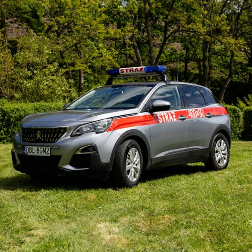Srebrny, operacyjny SUV marki Peugeot 3008 w wersji strażackiej. Wzdłuż nadwozia ciągnie się czerwony pas z białym napisem „STRAŻ” i numerem operacyjnym „400[D]92”. Na dachu, na czarnych relingach, zamontowana jest niebieska belka sygnalizacyjna z napisem „STRAŻ”. Pojazd stoi na trawie.