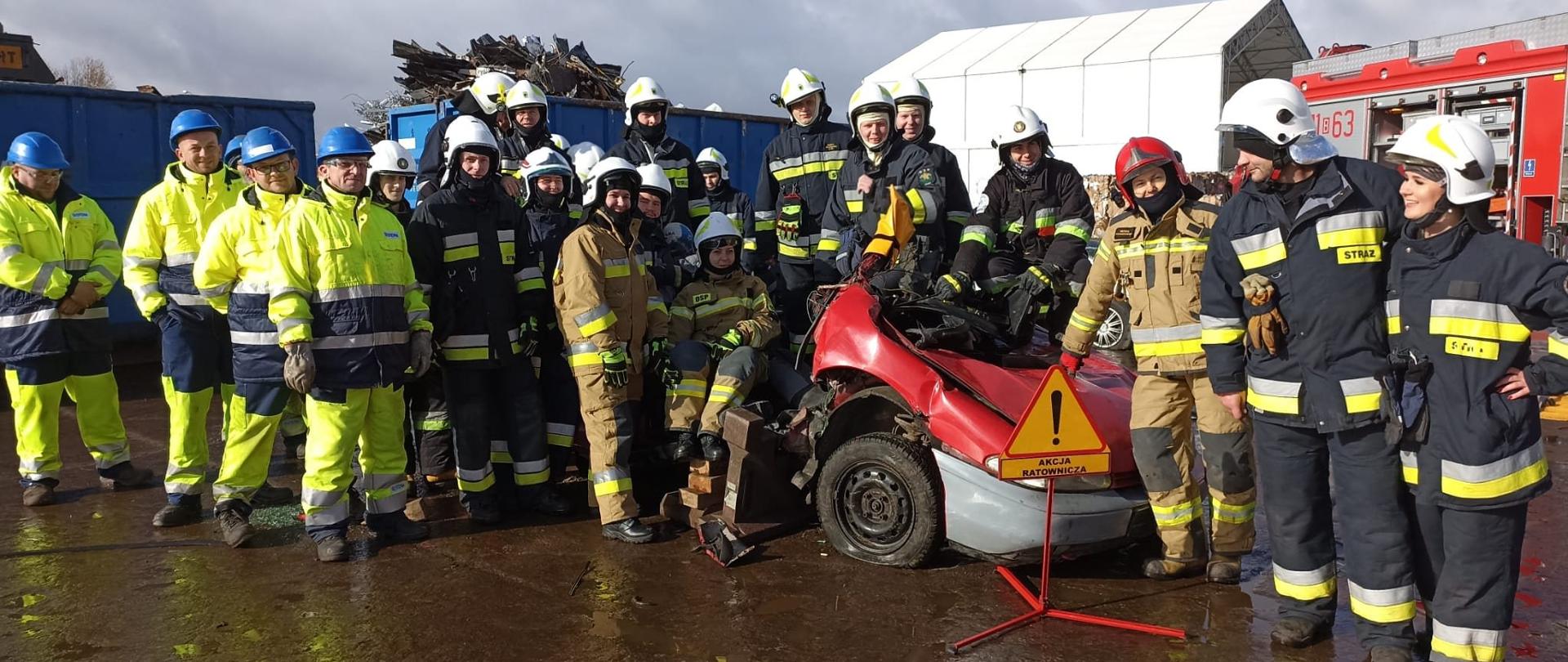 Na zdjęciu widać grupę kursantów szkolenia podstawowego OSP rozlokowaną wokół wraku pojazdu
