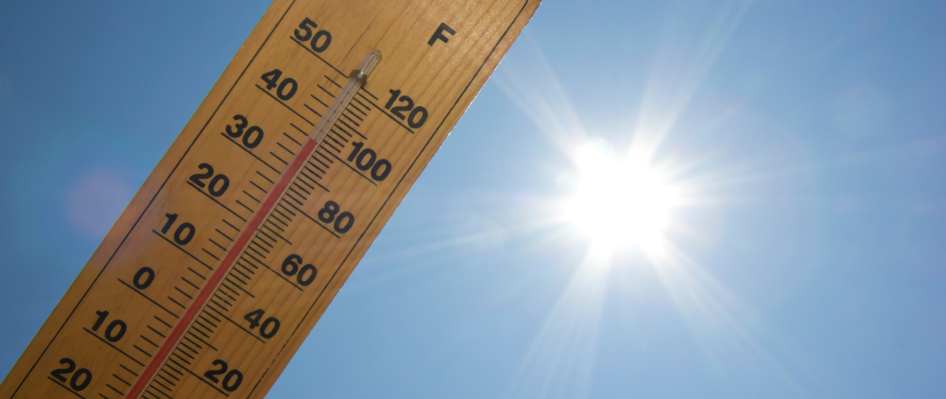 Na błękitnym słonecznym niebie termometr wskazujący wysoką temperaturę.