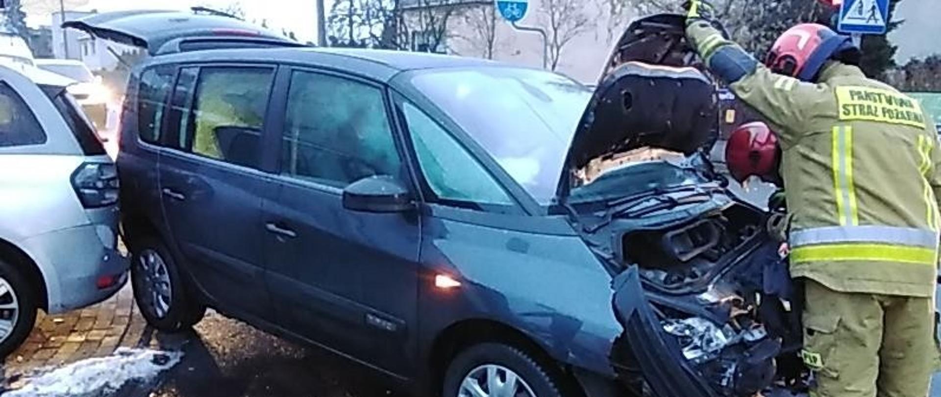 Dwa Uszkodzone samochody podczas kolizji, funkcjonariusze PSP podczas interwencji.