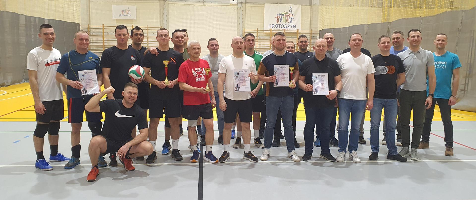 Pamiątkowe zdjęcie uczestników turnieju z Komendantem Powiatowym PSP . Wyróżnione drużyny trzymają w rękach pamiątkowe dyplomy i puchary, 