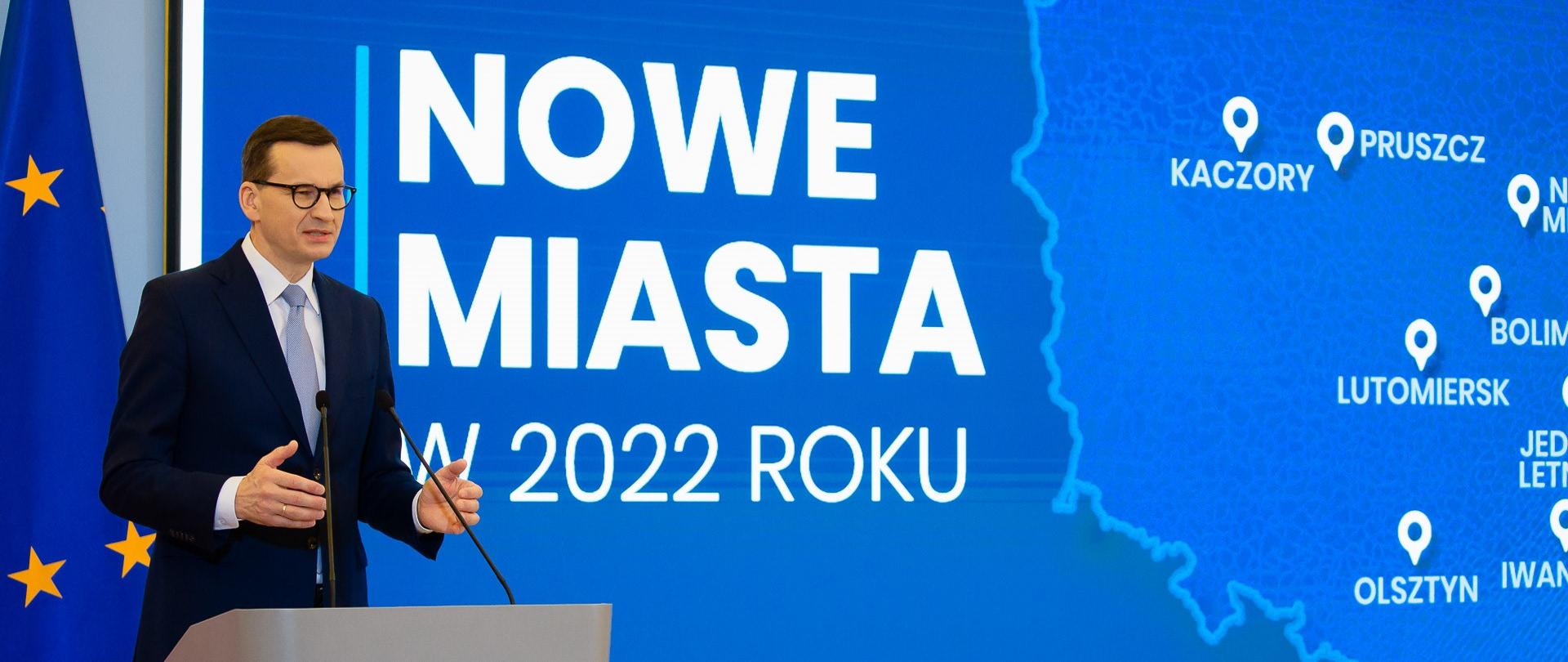 Premier przemawia na tle napisu: Nowe miasta w 2022 roku.