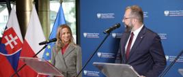 Konferencja prasowa ministra funduszy i polityki regionalnej Grzegorz Pudy i Dyrektor generalnej sekcji programów współpracy transgranicznej w słowackim resorcie inwestycji, rozwoju regionalnego i informatyzacji Lei Mali, za ich plecami flagi Polski, Słowacji i UE oraz baner MFiPR