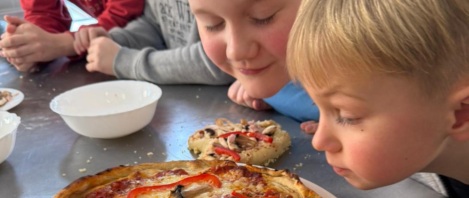 Kilku chłopców przygląda się upieczonej pizzy