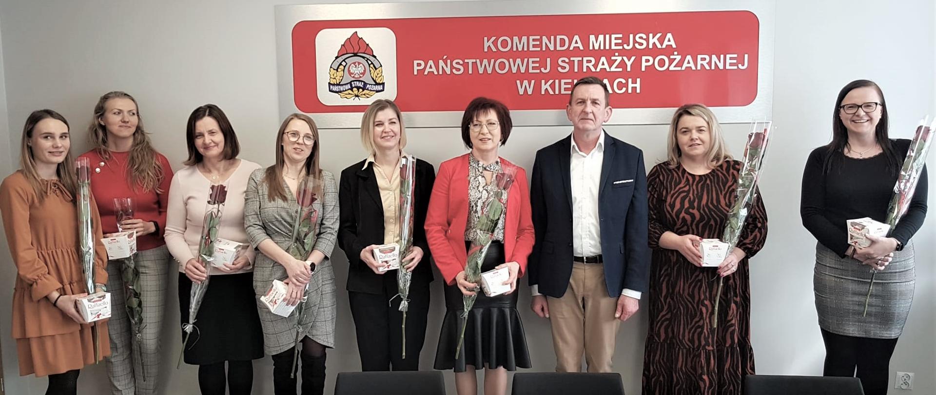 Zdjęcie przedstawia panie pracujące w Komendzie Miejskiej Państwowej Straży Pożarnej w Kielcach wraz z komendantem miejskim PSP st. bryg. Sławomirem Karwatem. 