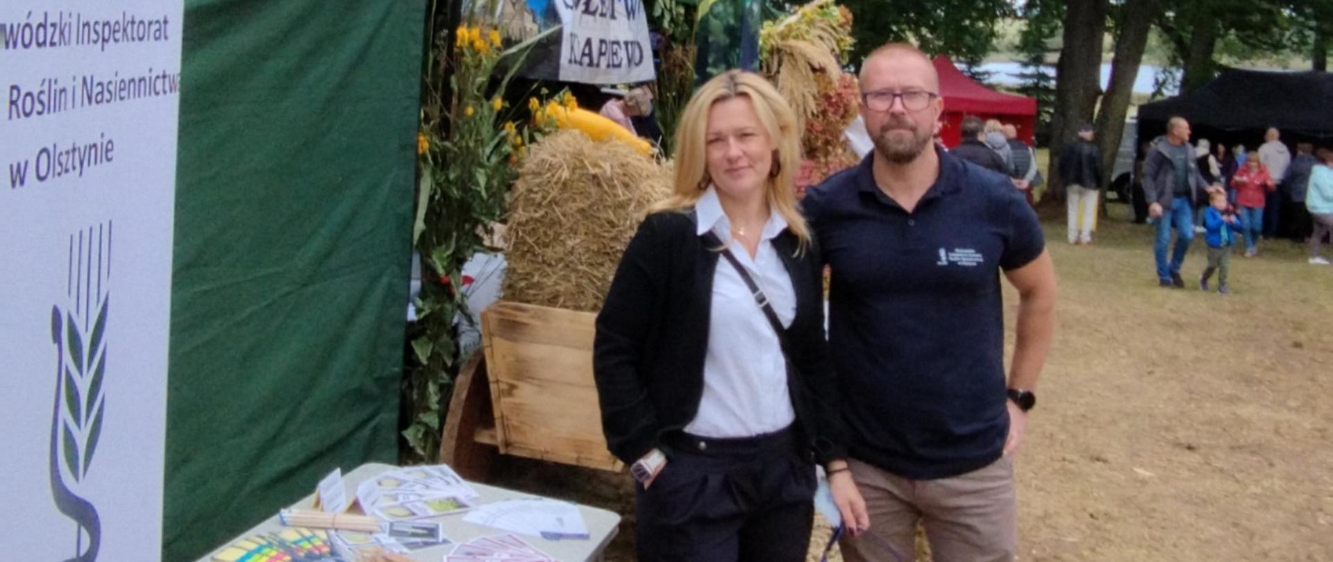  Pracownicy Inspekcji stoją przodem do zdjęcia. Po lewej stronie widać stanowisko z gadżetami oraz baner inspekcji. W tle widać innych wystawców oraz zwiedzających