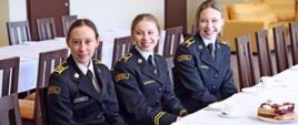 Trzy kadetki Centralnej Szkoły siedzące za stołem podczas uroczystości z okazji Dnia Kobiet