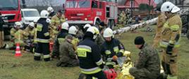 strażacy na stadionie trawiastym ćwiczą pomoc podczas wypadku samochodowego