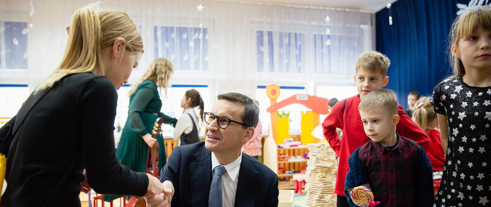 Premier wręcza dzieciom prezenty.