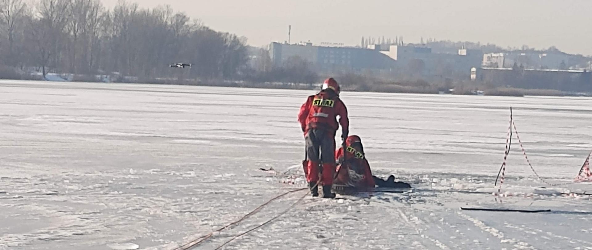 zdjęcie przedstawia osobę ratowana z wody, przy użyciu sań lodowych.