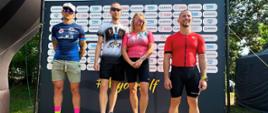 Zdjęcie przedstawia na podium zwycięzców Mistrzostwa Służb Mundurowych i Paramundurowych w ramach Garmin Triathlon Tour Rawa Mazowiecka 2026 w tlr baner z napisem garmin triathlon tour XV edycja