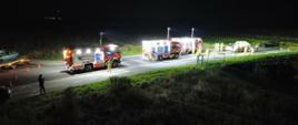 Trzy samochody pożarniecze oświetlają miejsce wypadku