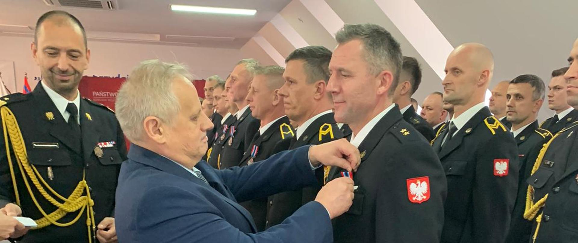 Mężczyzna wręcza odznaczenia strażakom