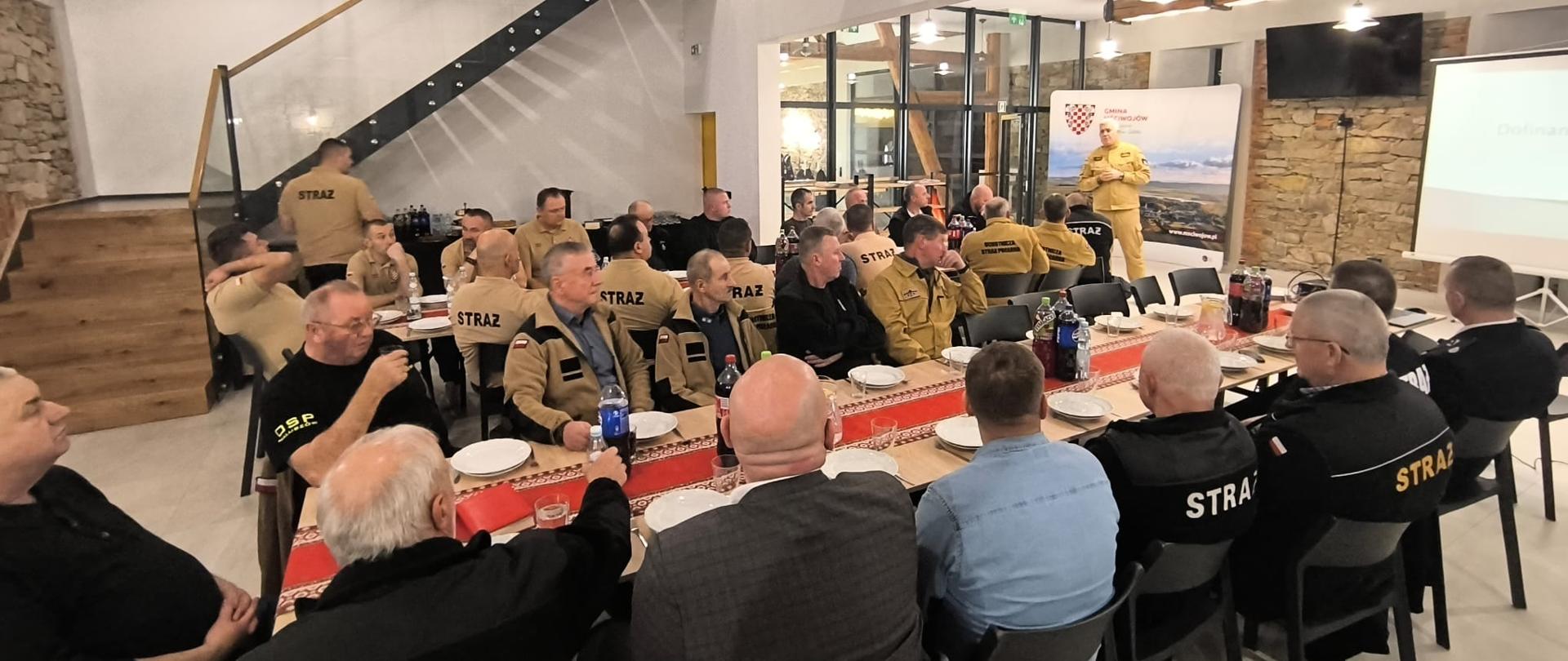 Komendant Powiatowy przemawia do prezesów i naczelników OSP siedzącch przy stolikach