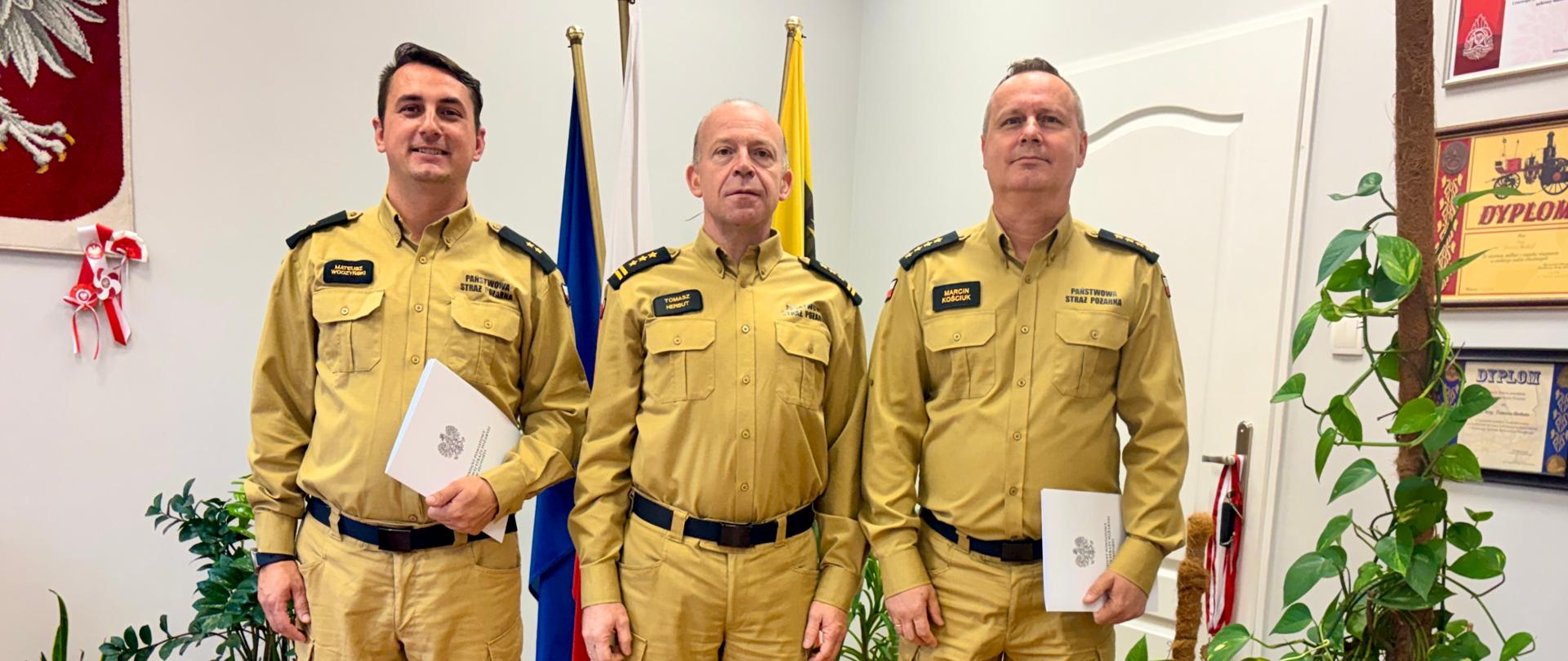Trzech strażaków stoi w szyku w gabinecie